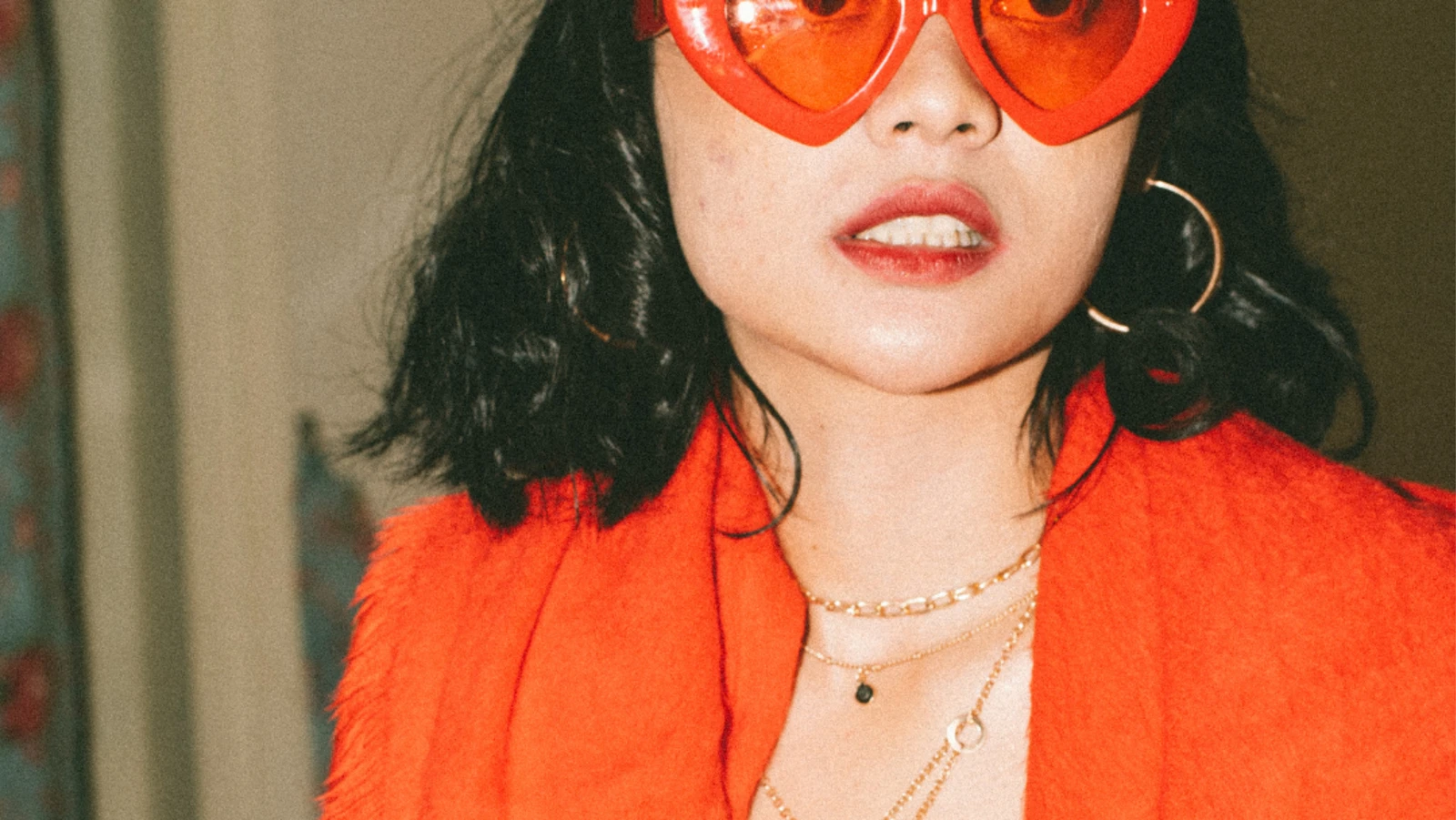 woman with big red heart glasses and red scarf posing